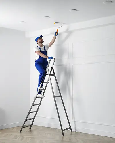 homme sur une échelle qui peint le plafond